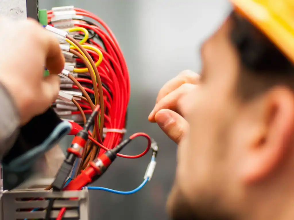 Electrician wiring a panel of cables